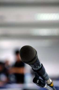 Seminer odası arkaplanının bulanık fotoğrafındaki mikrofon.