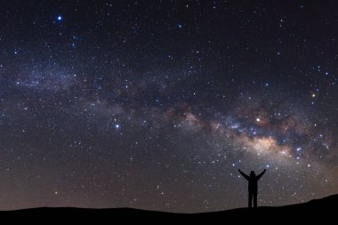 Samanyolu, gece gökyüzü yıldızlar ve ayakta sportif adamla silueti ile yüksek dağda silah kaldırdı ile manzara.