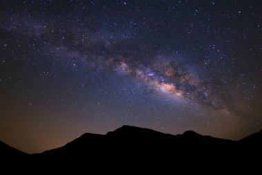Güzel Samanyolu Galaksisi ve yüksek dağlı silueti güneş doğmadan önce gece gökyüzünde.