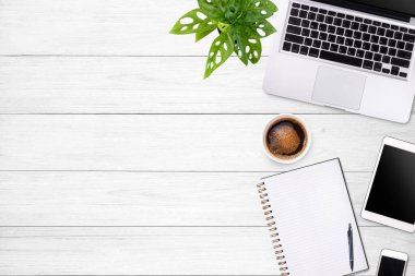 Laptop tableti, akıllı telefon ve kahve fincanı olan modern çalışma alanı beyaz ahşap masa arka planında. Üst Manzara. Düzleştirme biçimi.