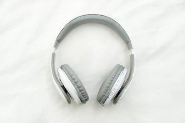 Beyaz kumaş arka planda bluetooth kulaklıklar