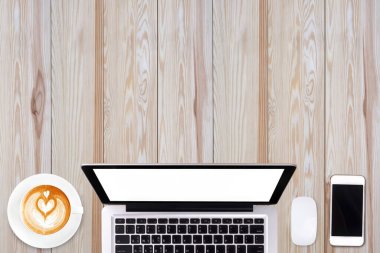 Üst görünüm dizüstü bilgisayar veya dizüstü bilgisayar, cep telefonu ve bir fincan latte sanat kahvesi ahşap masa üzerinde.