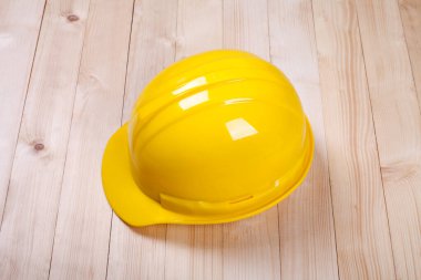 Kahverengi ahşap sırtüstü duran sarı şapkalı mimar