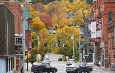 Corning, New York, ABD - 18 Ekim 2022 - Sonbahar yeşilliklerinin arka planına sahip kasabadaki trafik ve binaların manzarası