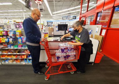 Wilmington, Delaware, ABD - 28 Mart 2023 - Bir müşteri şişe su satın alıyor ve kasiyer Staples 'dan mal alımını yapıyor.