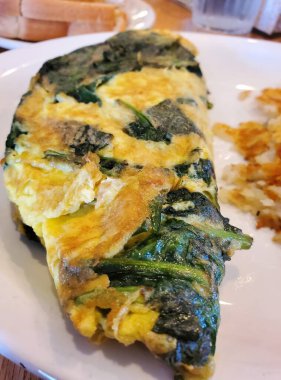 Beyaz seramik tabakta ıspanaklı omlet.