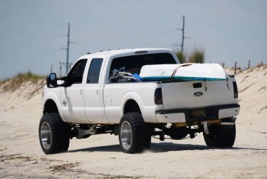 Savage Ditch, Delaware, U.S.A - July 4, 2023 - A white Ford truck with a kayak and surf fishing beach permit driving on the sand clipart