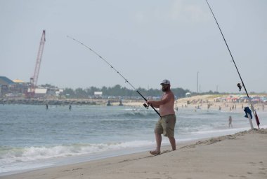 Bethany Sahili, Delaware, ABD - 8 Temmuz 2023 - Yazın sörf balıkçılığı sahilinde bir adam