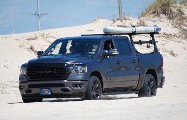Savage Ditch, Delaware, ABD - 4 Temmuz 2023 - Siyah bir Dodge Ram kano ve deniz kenarında sörf yapma izni olan bir kamyonet
