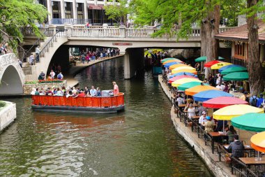 San Antonio, Teksas, ABD - 6 Nisan 2024 Renkli masa şemsiyeleri ve nehir yürüyüşündeki tekne