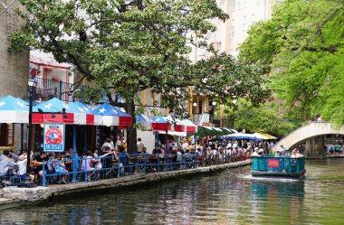 San Antonio, Teksas, ABD - 6 Nisan 2024 Nehir yürüyüşü ve geçen tekne yolculuğu boyunca restoranın masalarında oturan ziyaretçiler