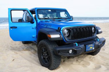 Lewes, Delaware, ABD - 4 Temmuz 2024 - Yeni 2024 Jeep Wrangler 4XE Willys hibrit plaja park etmiş mavi renkli
