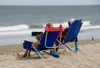 Rehoboth Beach, Delaware, U.S.A - September 2, 2024 - A couple enjoying and relaxing on the beach overlooking the bay clipart