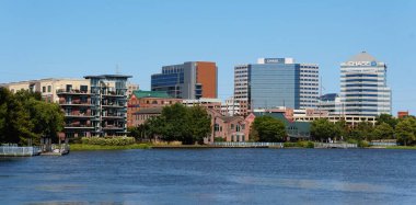 Wilmington, Delaware, U.S.A - September 8, 2024 - The distance view of the residential apartments, offices and downtown buildings seen from the Riverfront Park area overlooking Christina River clipart