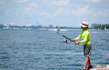 Key Biscayne, Florida, ABD - 20 Eylül 2024 - Florida Eyalet Parkı yakınlarında balık tutan genç bir çocuk