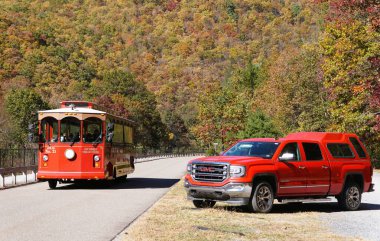 Jim Thorpe, Pennsylvania, ABD - 19 Ekim 2024 - Kırmızı GMC Sierra 4X4 kamyonu ve tepedeki sonbahar yeşilliklerinin canlı renklerine bakan tramvay turları