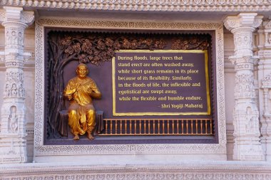 Robbinsville, New Jersey, U.S.A - Nov 9, 2024 - A golden statue of Shri Yogiji Maharaj displays a quote on flexibility and humble endure clipart