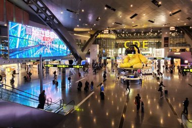 Doha, Katar - 18 Ocak 2025 - Modern mimariyle geniş alanda gezinen gezginlerle dolu hareketli bir havaalanı terminali