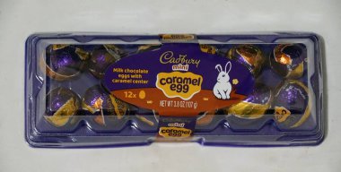 Delaware, U.S.A - 12 Nisan 2025 - Cadbury 'den 12 mini çikolatalı yumurta, her biri karamelli, mor ve berrak plastik bir kabın içine yerleştirilmiş.