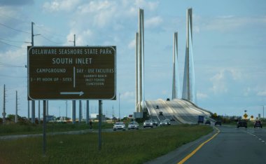 Delaware, ABD - 24 Mayıs 2025 - Delaware Sahil Parkı tabelası arka planda Indian River Köprüsü ile Güney Körfezi girişini gösteriyor