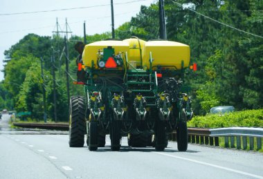 Maryland, ABD - 21 Mayıs 2025 - Tarım makineleri, sarı tanklarla sağlam bir tasarım, asfalt bir yolda ilerliyor.