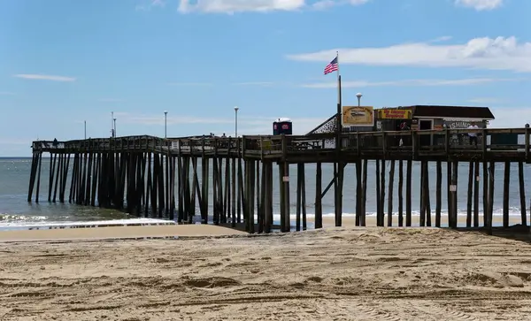 Okyanus Şehri, Maryland, ABD - 21 Mayıs 2025 - Okyanus boyunca uzanan yıpranmış ahşap iskele, kumlu sahili ve küçük bir balıkçı kulübesini gösteriyor..