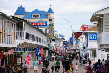 Okyanus Şehri, Maryland, ABD - 23 Mayıs 2025 - Güneşli bir günde ziyaretçi ve satıcılarla dolu hareketli tahta kaldırım sahnesi