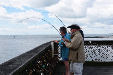 Okyanus Şehri, Maryland, ABD - 23 Mayıs 2025 Balıkçılar balıkçıların yakaladıkları balıkları, asma kilitlerle dolu bir zincir halkayla iskelede yakalıyorlar.