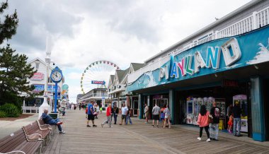 Ocean City, Maryland, ABD - 23 Mayıs 2025 Playland 'ın önünde ziyaretçilerin olduğu sahil yürüyüşü ve lunaparkın arka planı