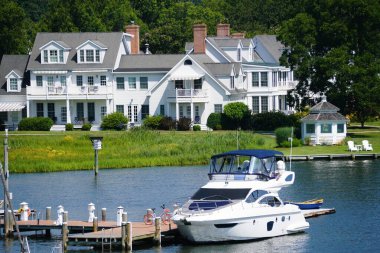 St Michaels, Maryland, ABD - 29 Haziran 2025 - Huzurlu deniz kenarı evleri, rıhtımda yuva yapmış bir tekne.
