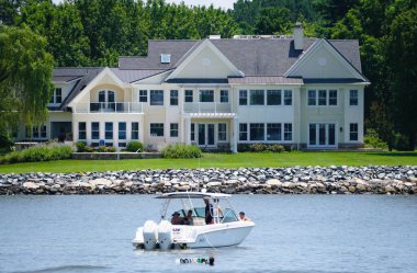 St Michaels, Maryland, ABD - 30 Haziran 2025 - Huzurlu su yolu boyunca süzülen bir tekne ile lüks liman bölgesi.