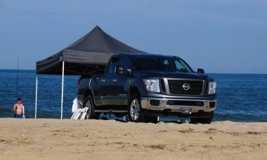 Lewes, Delaware, ABD - 12 Temmuz 2025 - Siyah bir Nissan Pathfinder, koyu renkli bir çadırla plaja park etmiş.