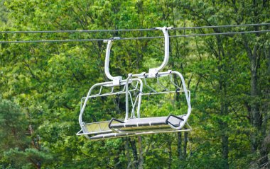 Camelback Dağı, Tannersville, Pennsylvania, ABD yakınlarında güneşli bir günde yemyeşil orman tepe örtüsünün ortasında asılı duran boş kayak arabası..