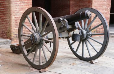 Antika bir top taş bir verandada duruyor, tahta tekerlekleri ve koyu metal fıçıları, Fort Delaware, ABD 'de gösterilen eski bir dönemin kanıtı.