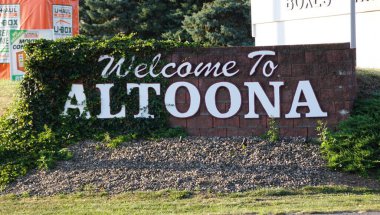 Altoona, Pennsylvania, ABD - 9 Ağustos 2025 - Sarmaşıkla süslenmiş tuğla bir karşılama tabelası, Altoona 'ya gelen ziyaretçileri selamlıyor.