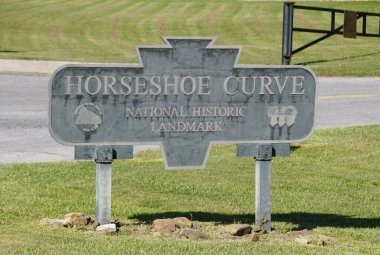 Altoona, Pennsylvania, ABD - 9 Ağustos 2025 - Tarihin sessiz bir işareti olan Horseshoe Curve National Historic Landmark tabelası, çimenli bir alanda bulunur..