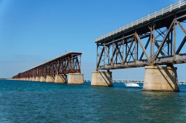 Terk edilmiş Bahia Honda Demiryolu Köprüsü 'nden geçen küçük beyaz bir tekne.