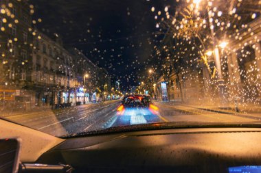 Gece araba trafiği yağmur damlası ön camından görülebilir.