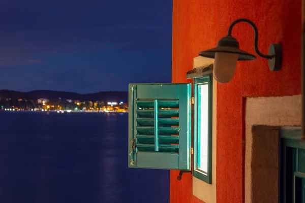 克罗地亚Rovinj老城一间有百叶窗的房子的窗户 后面是一个有小灯的海湾 — 图库照片