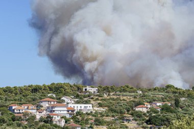 Hırvatistan 'ın Adria sahilindeki güneşli yaz gününde dumanlı ve dilli Bush yangını, telefon lensleri