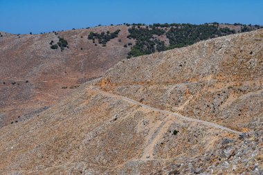 Kırmızımsı renkli çorak kayalık dağlar, yol, açık mavi gökyüzü, güneşli, manzara, Yunanistan, Girit adası, telefoto
