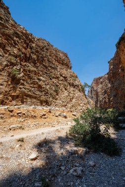 Aradena boğazının dik kaya duvarları arasındaki turistik yol, açık mavi gökyüzü, güneş, manzara, Yunanistan, Girit adası, geniş açılı mercek