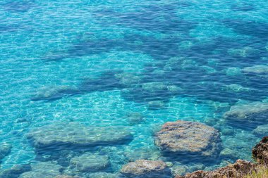 Plajda kayalarla, güneşle, manzarayla, Yunanistan 'la, Girit adasıyla, telefoto ile berrak, mavi ve şeffaf sular.