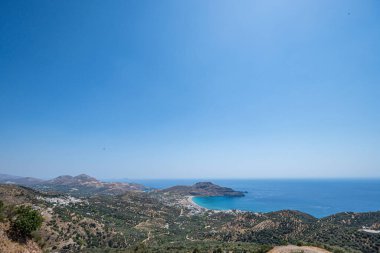 Dağlı sahil, yeşil bitkiler ve açık mavi gökyüzü olan küçük kasaba, Myrthianos Plakias, Yunanistan, Girit Adası, geniş açılı mercek