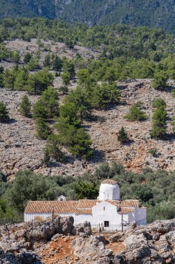 Dağlardaki geleneksel kilise, kayalar ve dağınık çam ağaçları, güneş, Yunanistan, Girit adası, telefoto