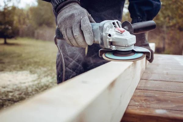 Man using electric grinder to polish wood plank