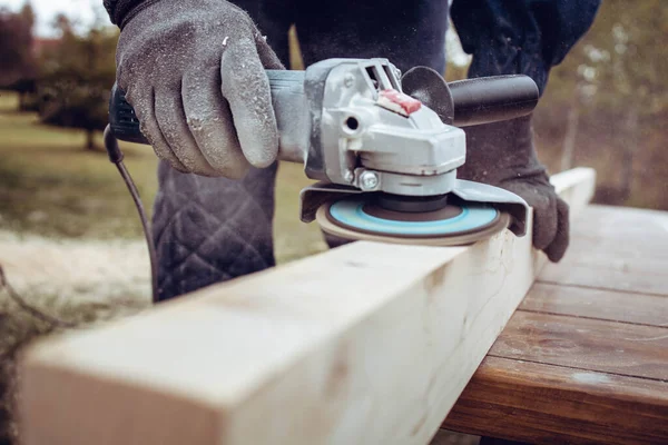 Man using electric grinder to polish wood plank