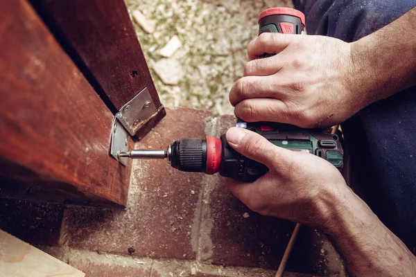 Handyman screwing a door hinge in the wooden door frame. Home renovation