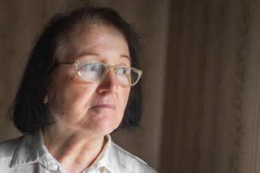 Ayakta duran ve pencereden bakan yaşlı kadın.