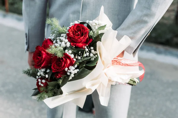 Close-up of a man holding rose bouquet behind his back. Valentines day